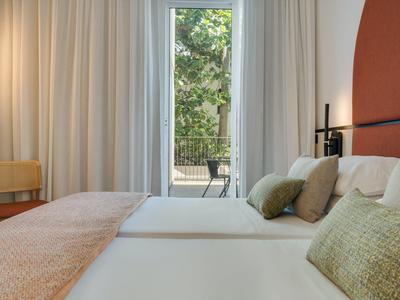 Hotelzimmer mit zwei Betten, beigen und grünen Kissen und Blick auf einen Balkon