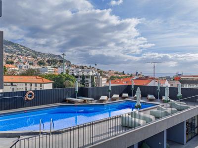 Terrasse sur le toit moderne avec piscine et vue sur la mer dans une ville côtière.