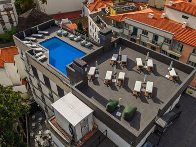Terrasse sur le toit avec des chaises longues et une piscine sur un bâtiment hôtelier.