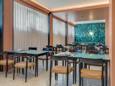 Salle à manger moderne avec chaises en bois, tables et mur bleu décoratif dans un hôtel.
