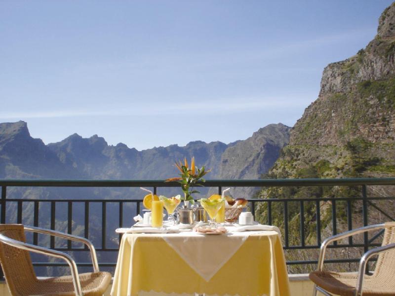 Table with yellow tablecloth and breakfast on balcony with mountain view