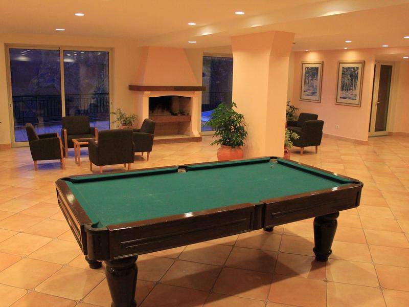 Bright hotel room with two single beds, green bedspread, balcony with sea view, and wooden floor.