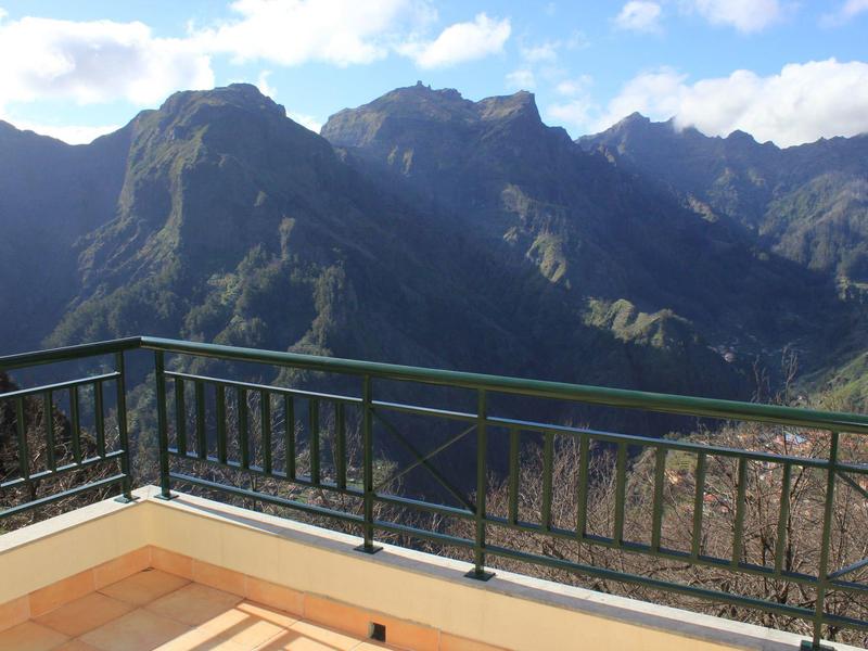 Mountain view with balcony and green railing under blue sky