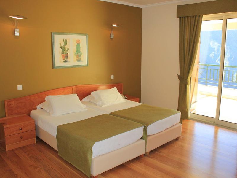 Simply furnished hotel room with two beds and balcony overlooking mountains
