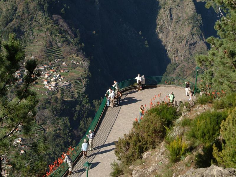 Viewing platform with people overlooking a village in a deep valley