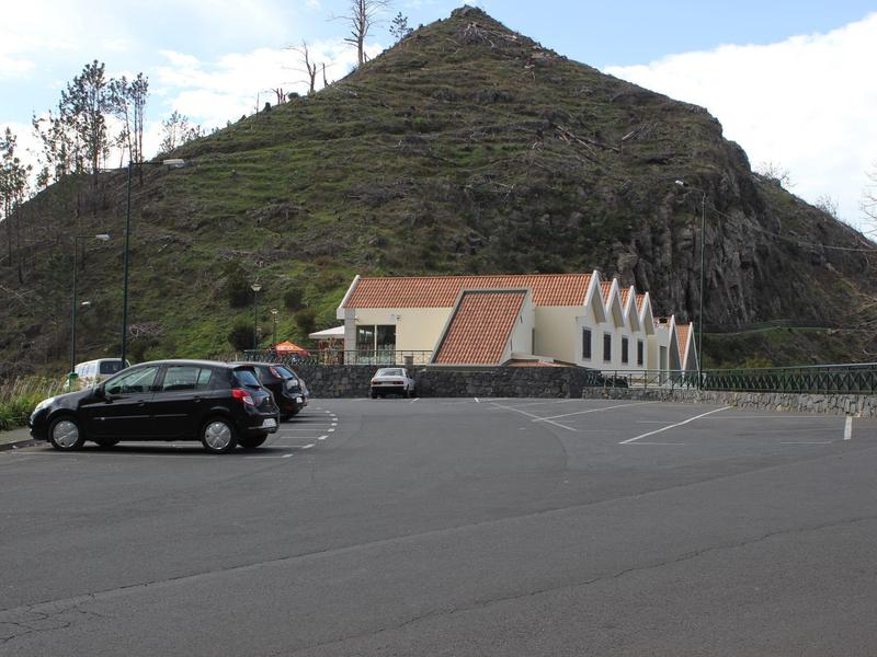 Multi-story hotel building on a hillside overlooking a road, surrounded by trees.