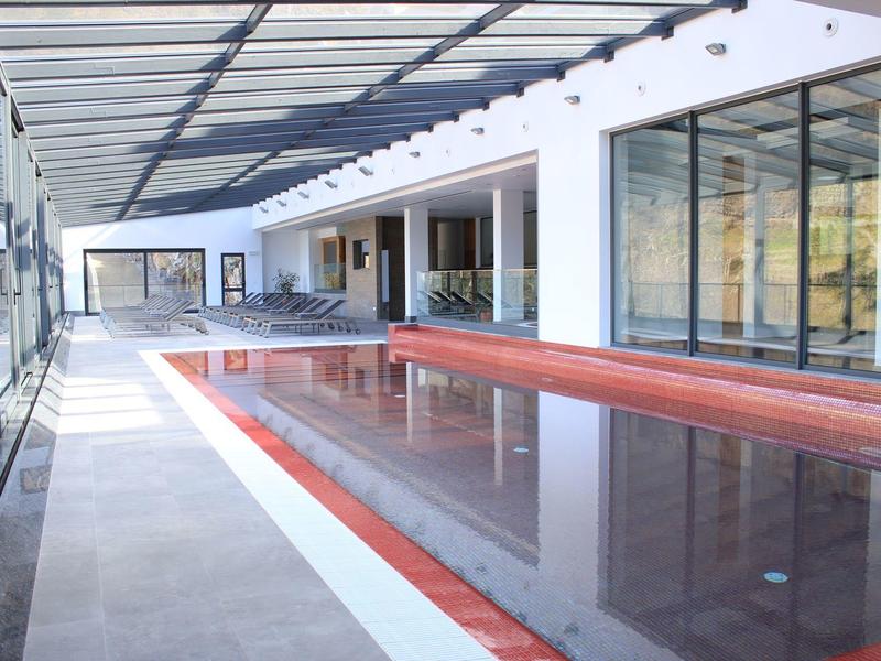 Modern indoor pool with sunroof and large windows in a hotel setting.