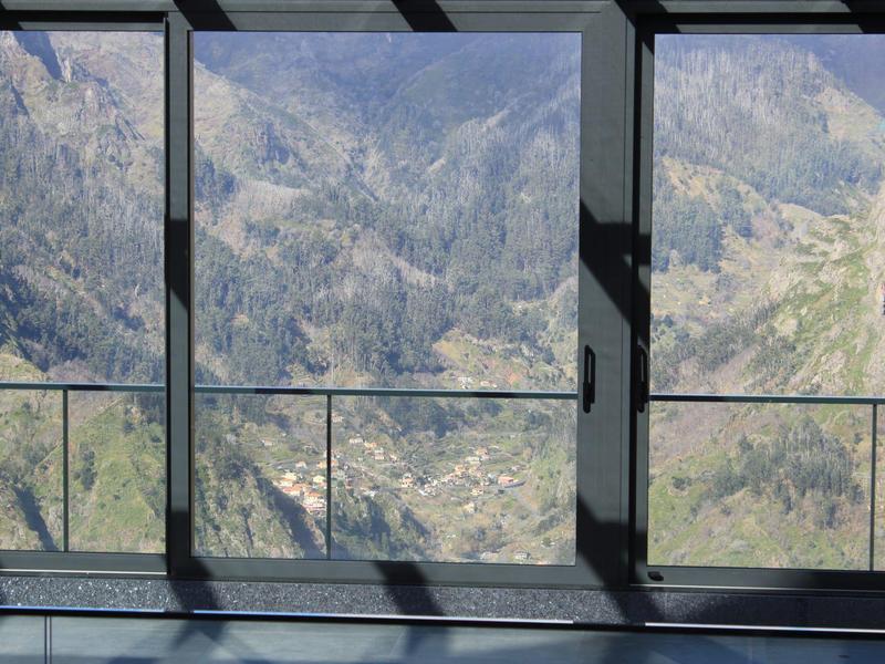 Mountain view through large glass windows with metal frames in a modern building.