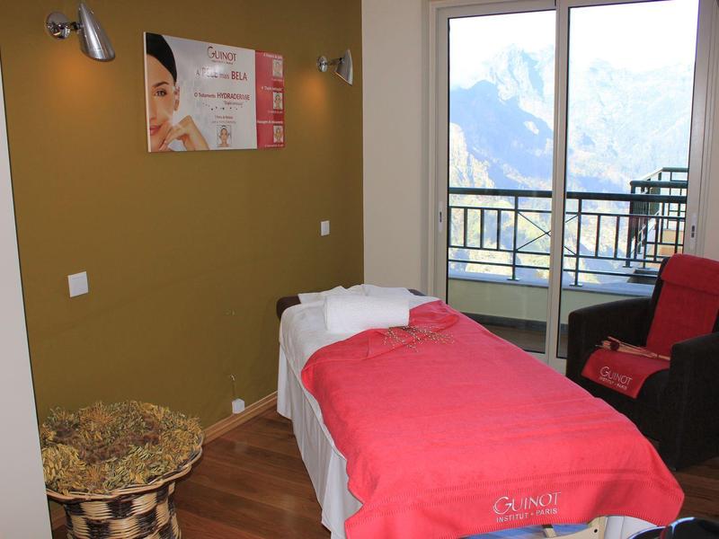 Cozy wellness room with massage table and balcony overlooking mountains.