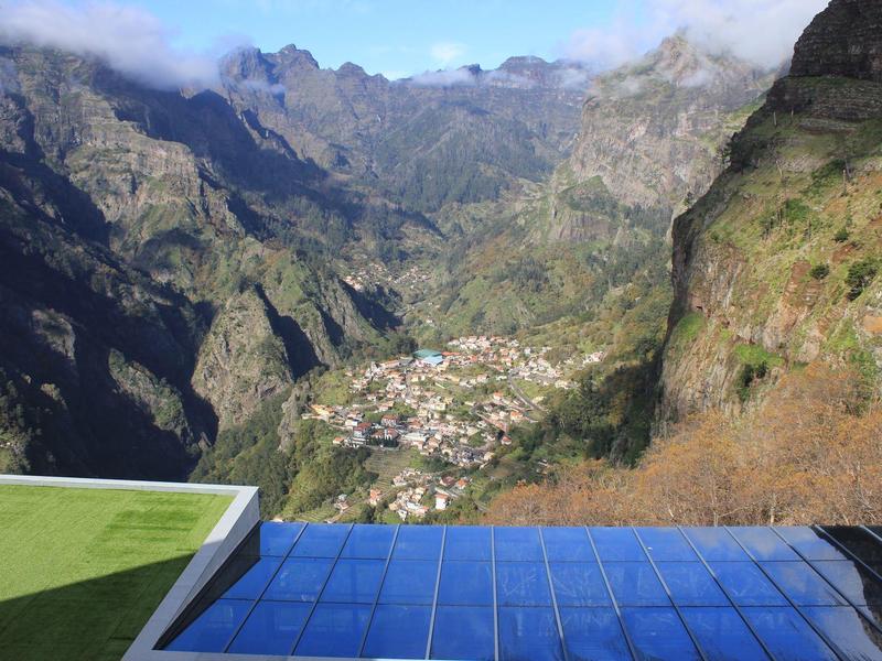 View from a hotel with pool overlooking a mountain valley with village in the distance.