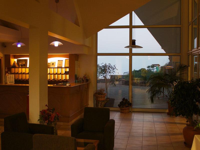 Cozy hotel lobby with seating area, large windows, and sea view at dusk.