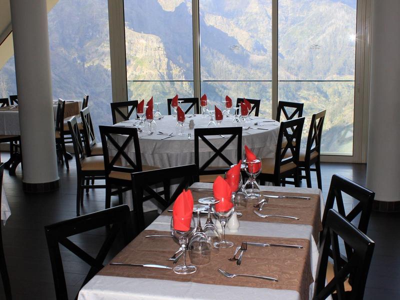 Elegant restaurant with neatly set tables and panoramic mountain view.