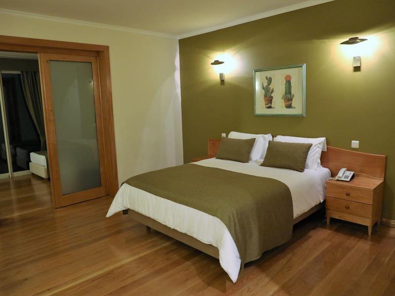 Bedroom with double bed, green accent wall, nightstands, and wooden floor.