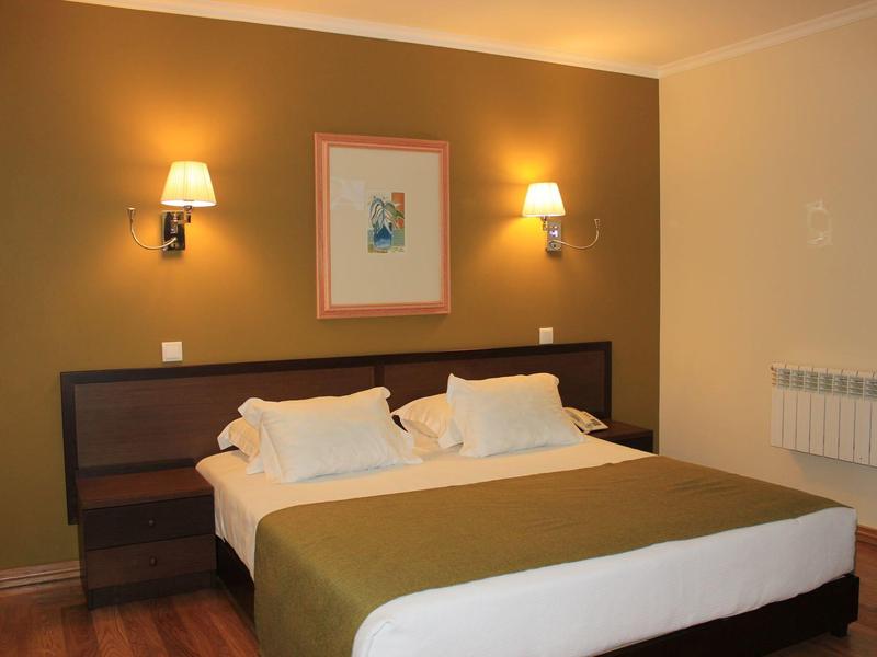 Cozy hotel room with double bed, warm lighting, and simple wall art.