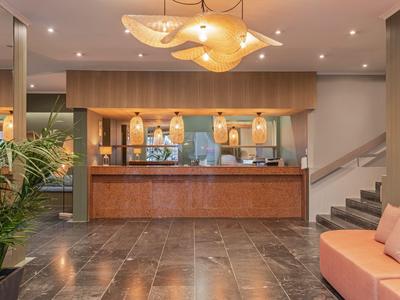 Moderne Hotellobby mit Holzempfangstresen, Sitzbereich und warmen Lichtakzenten.
