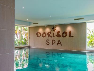 Modernes Hallenbad im Dorisol Spa mit großen Fenstern und Blick ins Grüne.