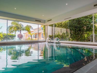 Innenpool mit großer Fensterfront und Blick auf Garten und Häuser.