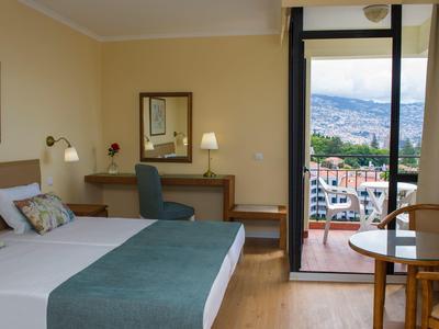 Gezellige hotelkamer met tweepersoonsbed, bureau en balkon met uitzicht op de stad.