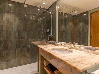 Modernes Badezimmer mit Marmor-Waschtisch, zwei Waschbecken, großer Spiegel und Dusche mit Glaswand.