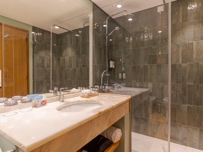 Moderne Badezimmereinrichtung mit zwei Waschbecken und großer Glasdusche.