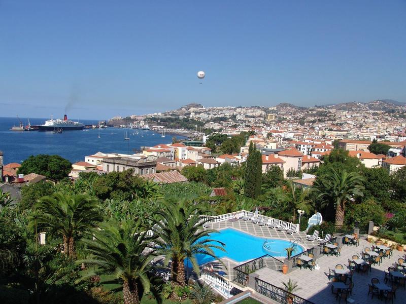Stadtansicht mit Pool, Palmen, Gebäuden und klarem blauem Himmel am Meer.