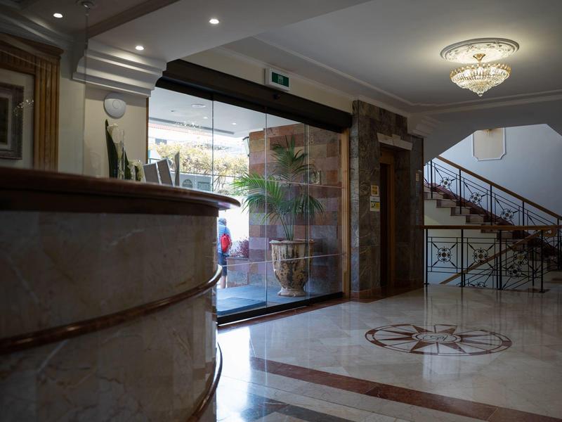 Elegante Hotellobby mit Marmorboden, Empfangstresen und Treppe mit Metallgeländer.