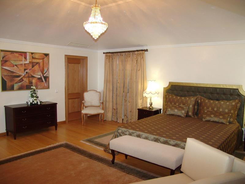 Gemütliches Schlafzimmer mit Holzboden, braunem Bett, weißen Stühlen und warmem Licht.