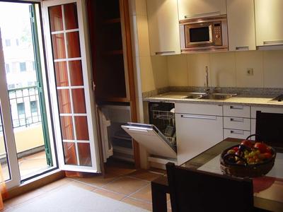 Moderne kitchenette met open kastdeuren en toegang tot balkon met reling