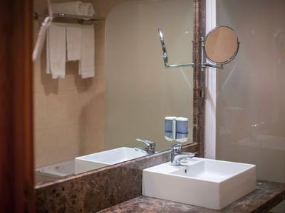 Moderne hotelbadkamer met wastafel, spiegel, handdoeken en marmeren aanrecht.