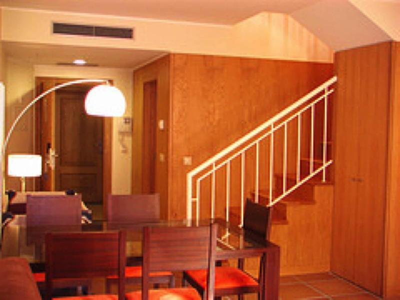 Gezellige eetruimte met houten trap en moderne lampen in een hotelkamer.