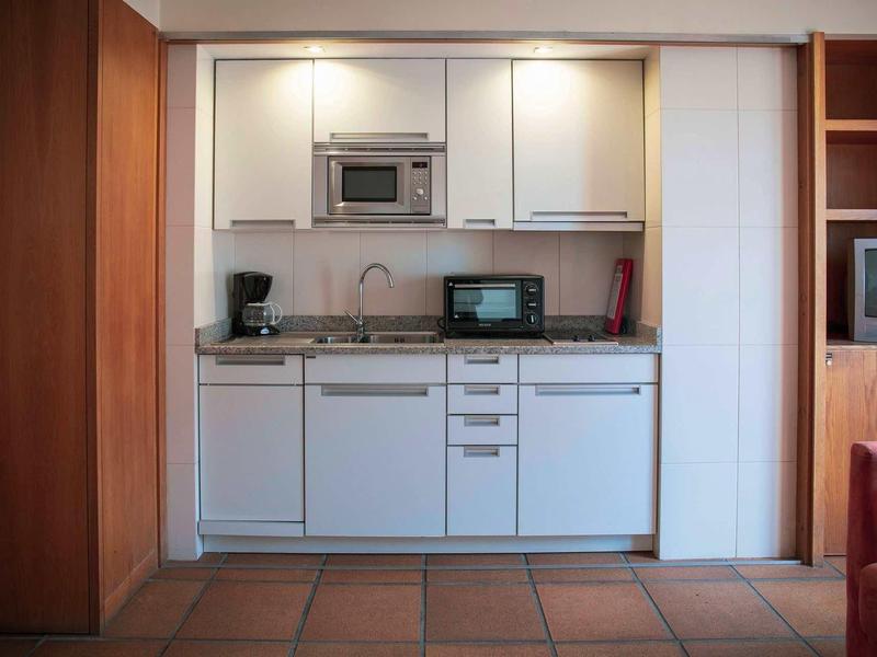 Compacte kitchenette met witte kasten, magnetron, koffiezetapparaat en broodrooster.