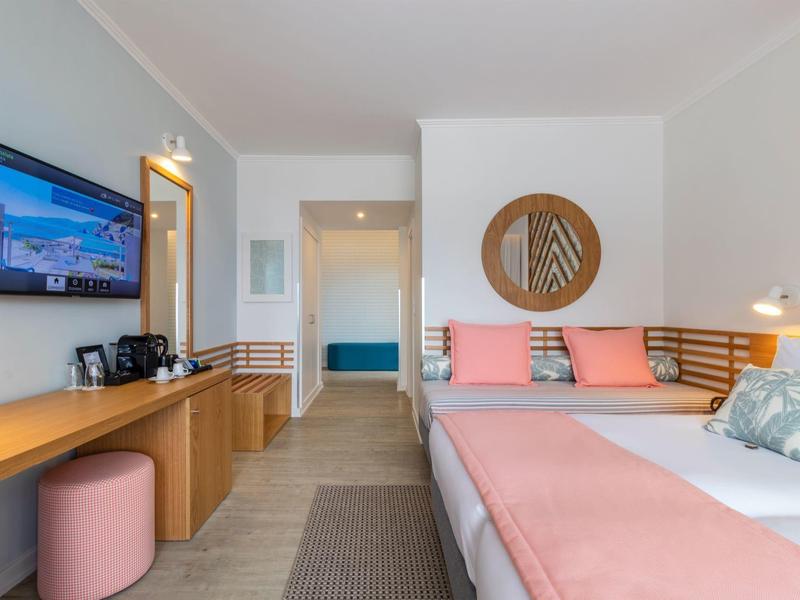 Helles, modernes Schlafzimmer mit Doppelbett, holzfarbenen Möbeln und rosa Akzenten.