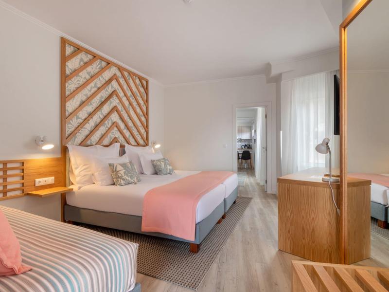 Modernes Schlafzimmer mit Doppelbett, Holzmöbeln, rosa Akzenten und hellem Parkettboden.