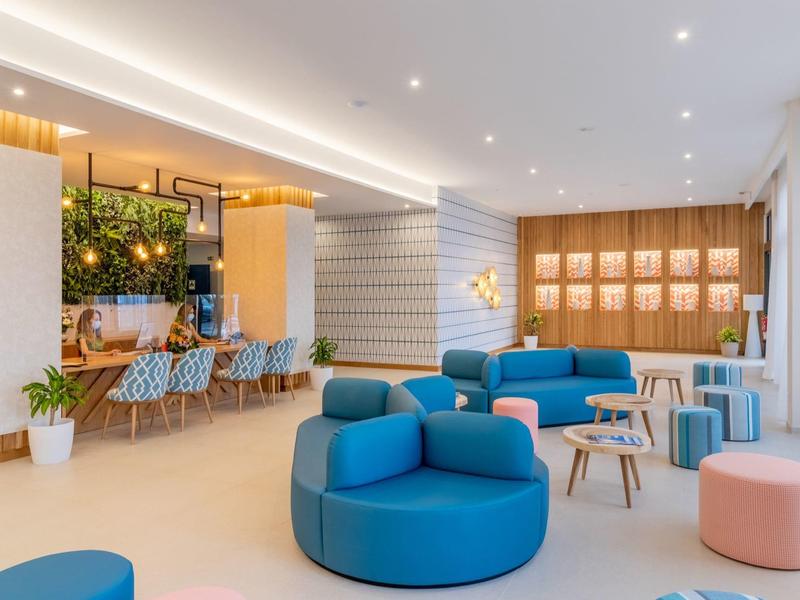 Moderner Wartebereich mit blauen Sesseln, Holzverkleidung, Pflanzen und hellen Wänden.