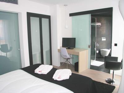 Camera d'hotel moderna con letto, scrivania, sedia e vista sul bagno con WC.