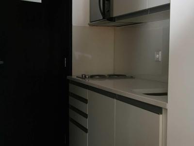 Angolo cottura compatto con microonde, piano cottura e armadietti in uno spazio ridotto.