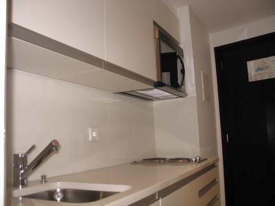 Angolo cottura moderno con lavandino, fornello e microonde in una stanza d'hotel.