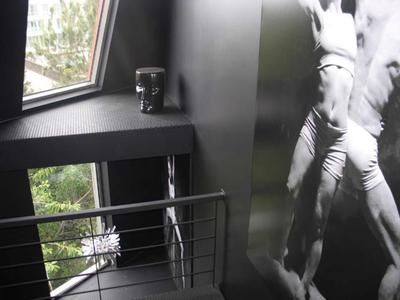 Blick auf eine moderne, dunkle Hotelzimmer-Ecke mit Fenster, Geländer und großem Schwarz-Weiß-Foto an der Wand.