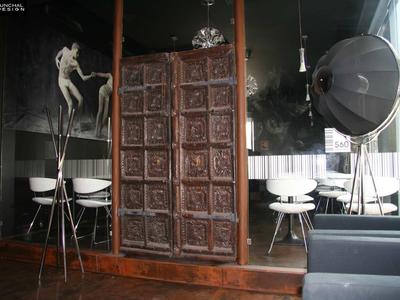 Stanza moderna con pareti scure, eleganti sedie bianche e grande pannello di legno.