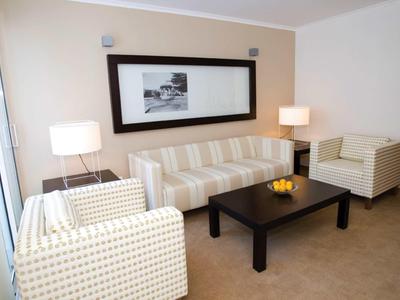 Soggiorno moderno con divano, poltrone, lampade e tavolo nero con decorazioni.