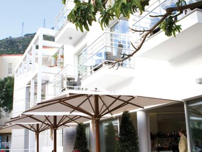 Area esterna di un hotel moderno con tavoli e ombrelloni, persone sedute che si godono.