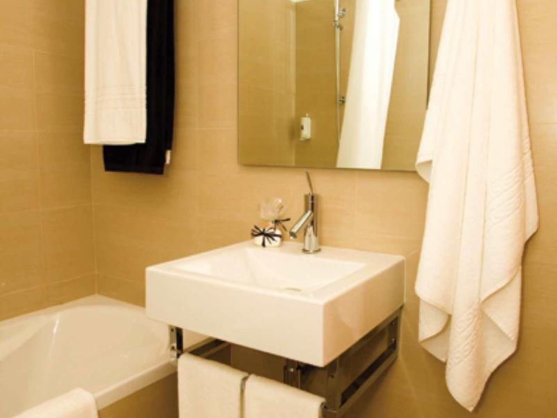 Bagno moderno con lavabo, specchio, vasca da bagno e asciugamani puliti.