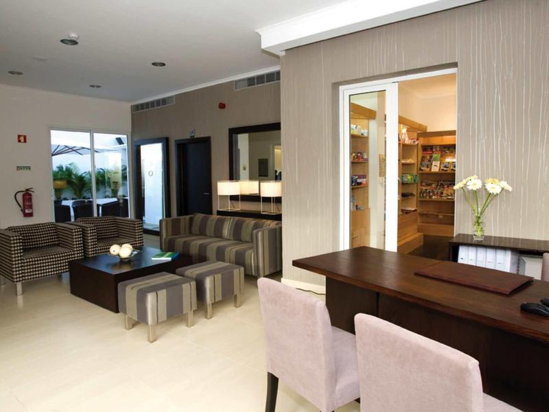 Area lounge di un hotel moderna e accogliente con divani, tavoli e mobili in legno.