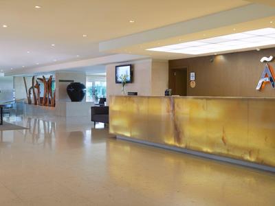 Moderner Empfangsbereich mit goldfarbenem Tresen, hellen Wänden und skulpturaler Dekoration.