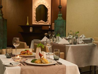 Elegantes Restaurant mit gedeckten Tischen, weißen Tischdecken und dekorativen Kerzenhaltern.