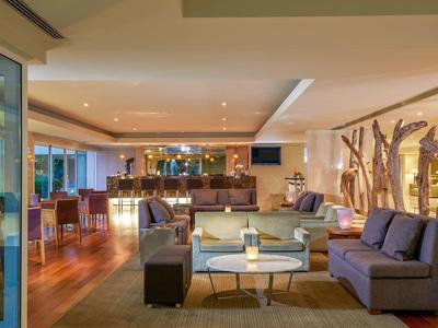 Helles Wohnzimmer mit Holzboden, mehreren Sofas, Holzdekoration und gedeckter Beleuchtung.