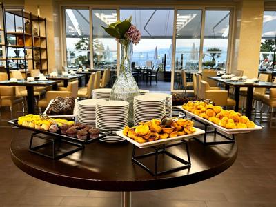 Buffet table with fresh pastries and flower arrangement in a bright dining room with window views.