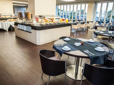 Hell eingerichteter Speisesaal mit Buffetbereich und modernen Tischen und Stühlen.