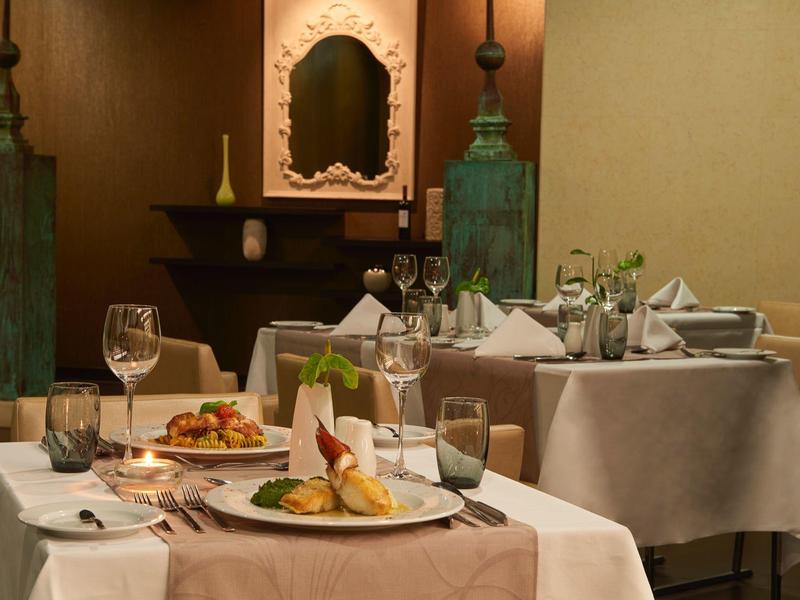 Elegantes Restaurant mit gedeckten Tischen, weißen Tischdecken und dekorativen Kerzenhaltern.