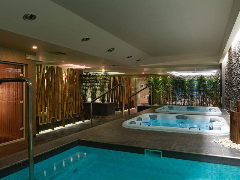 Ein moderner Wellnessbereich mit Pool, Whirlpool und warmem Licht in hellem, gemütlichem Ambiente.